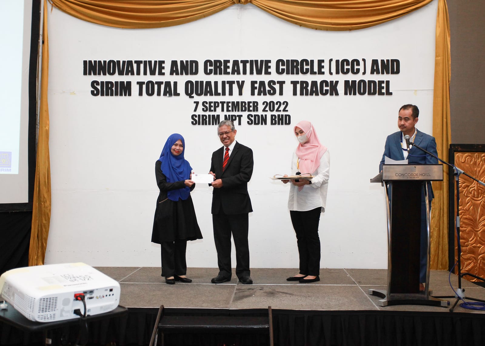 Presenters on stage beneath the ICC and SIRIM Total Quality Fast Track Model banner