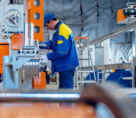 A technician in overalls operating machinery on a production line