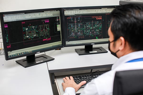An engineer working on CAD drawings across two monitors